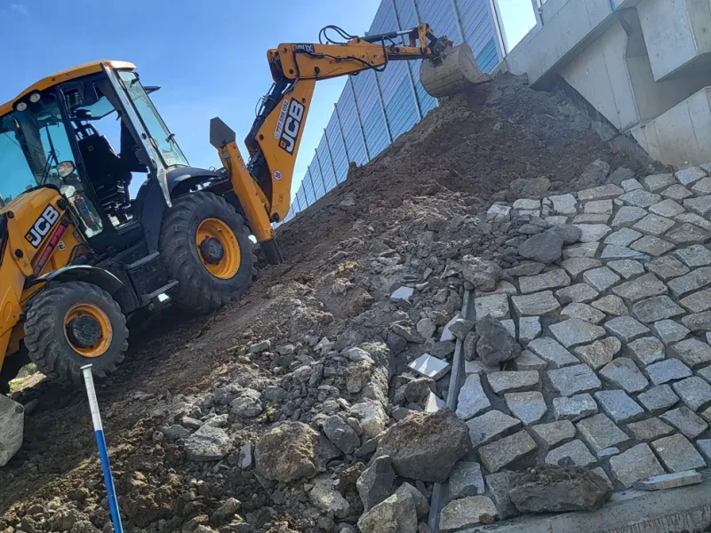 Bagr při úpravě svahu a bouracích pracích
