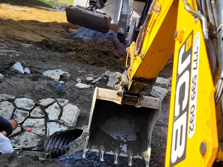 Traktorbagr při práci na kamenném svahu
