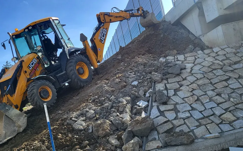 Bagr při úpravě svahu a bouracích pracích