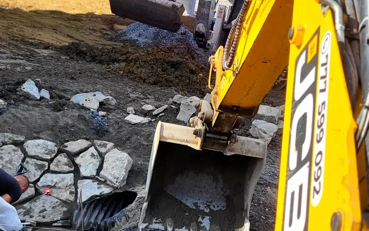 Traktorbagr při práci na kamenném svahu
